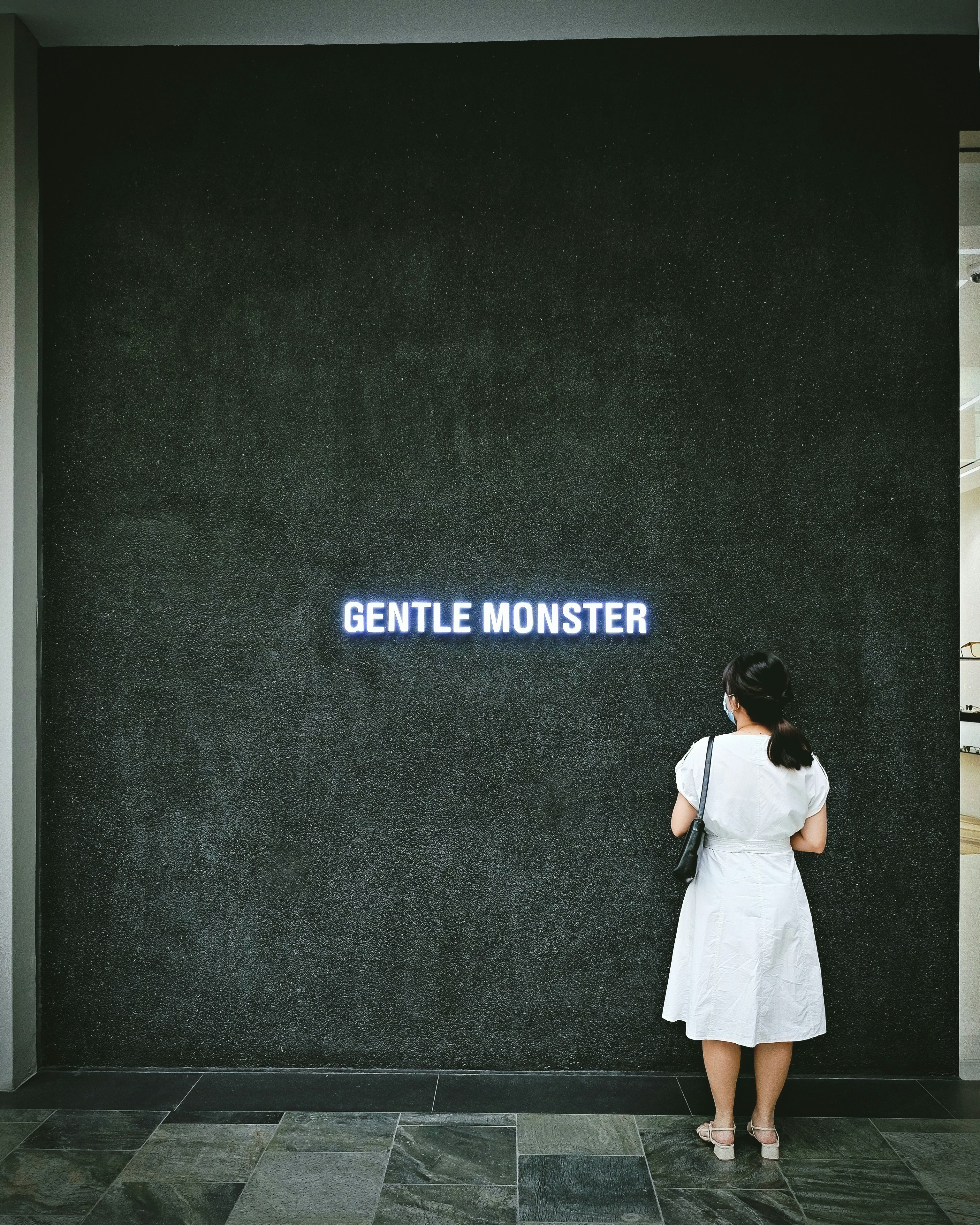 woman in white dress standing in front of black and white wall